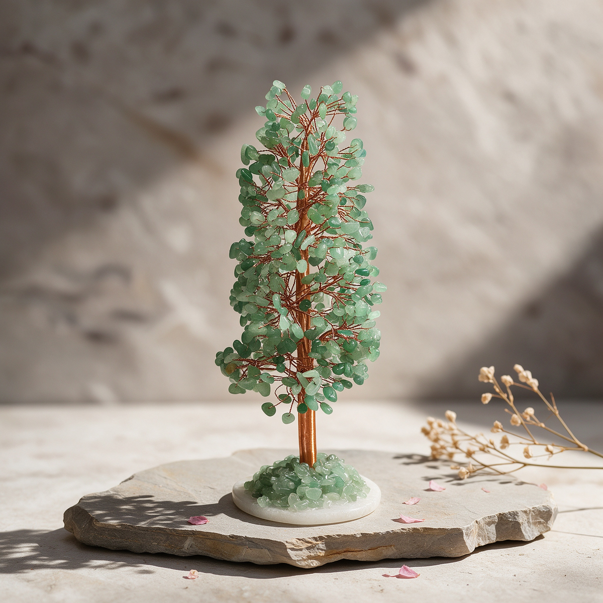 Natural green aventurine crystal tree with a slim columnar canopy of jade-green gemstone chips on red copper wire branches, rooted in matching green aventurine chips on a polished white clear quartz disc, styled on a rustic stone slab in soft natural light
