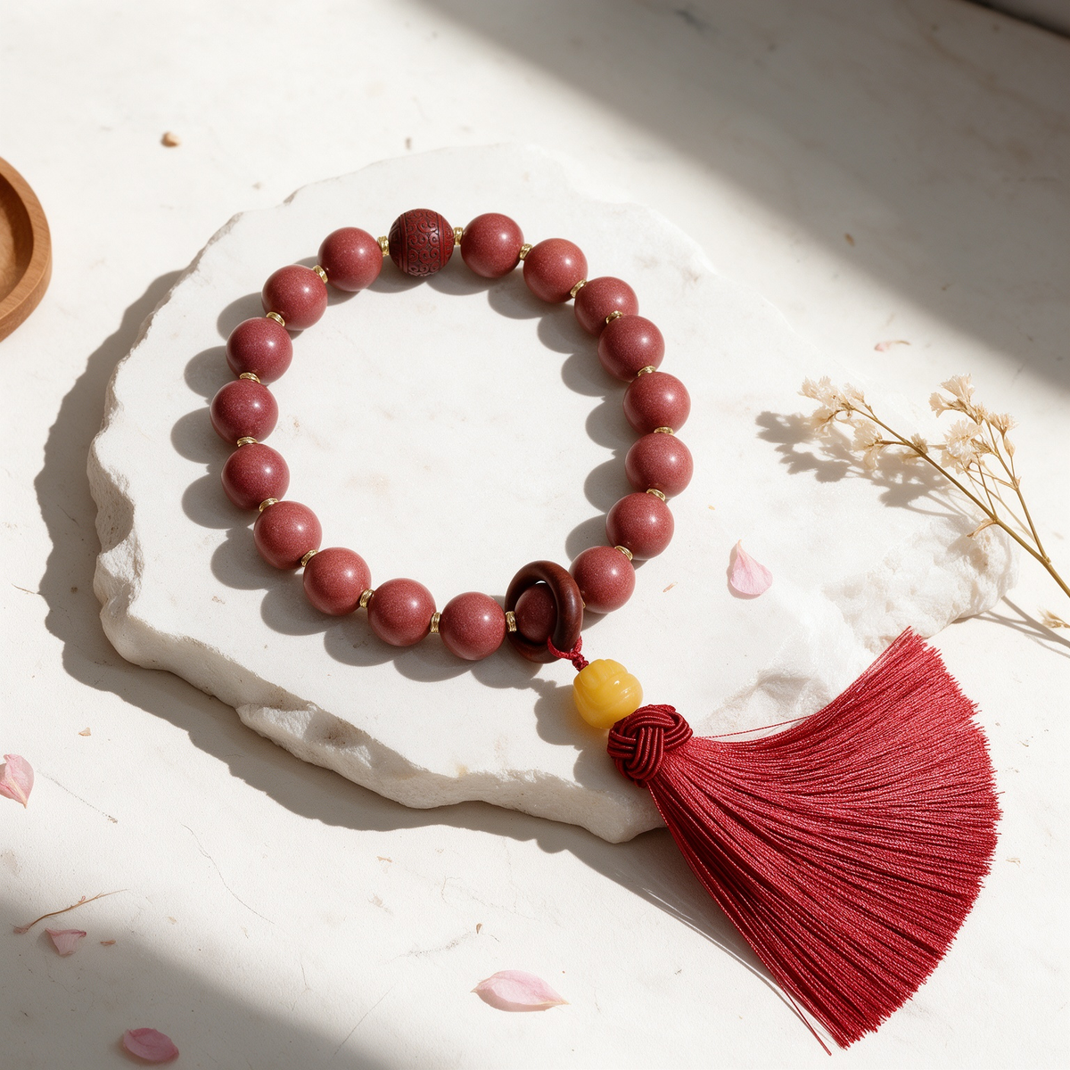 Rose-toned scented bead handheld strand with red tassel, close-up detail