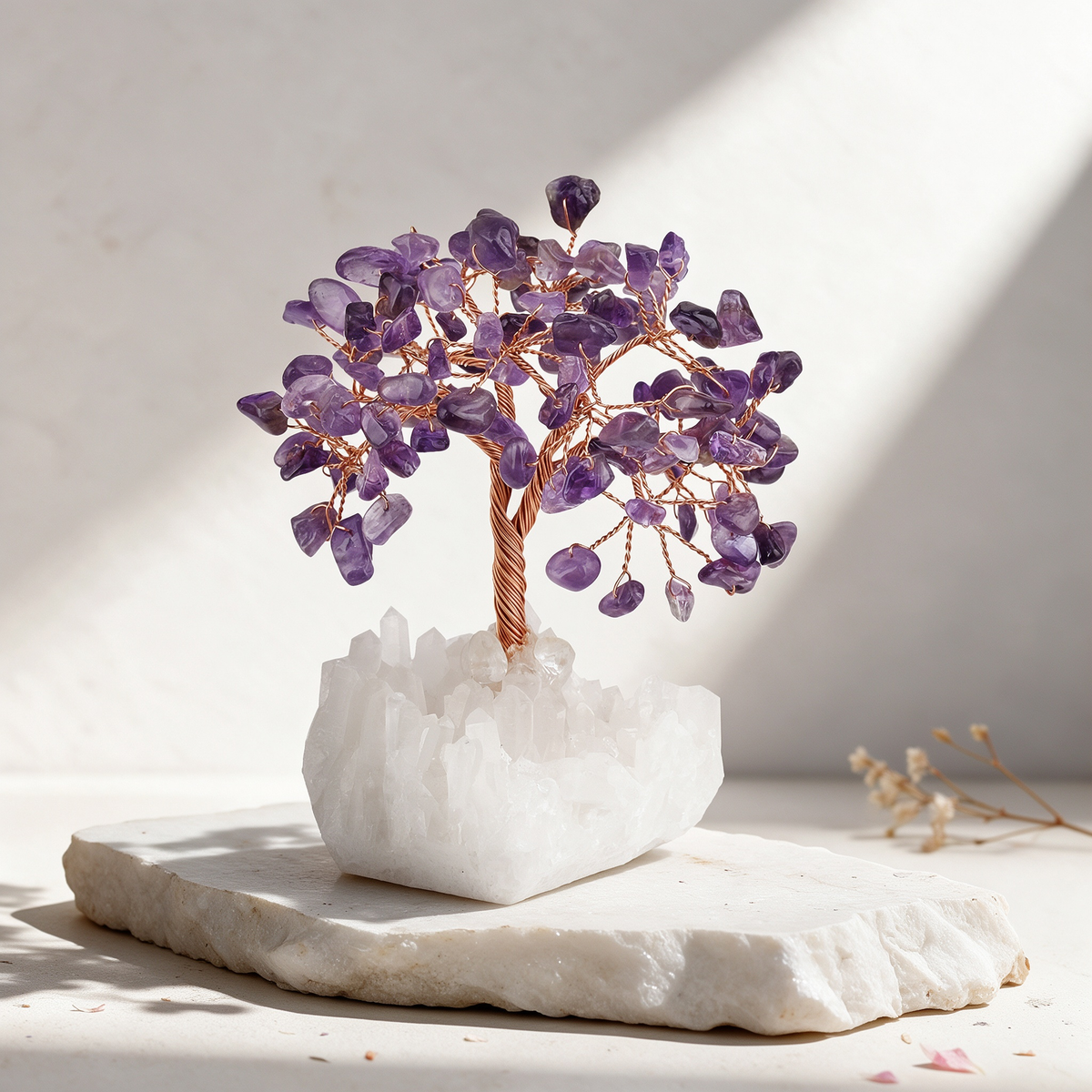 Amethyst crystal tree with translucent purple chip leaves on a hand-twisted copper wire trunk, rising from a raw clear quartz cluster base, displayed on a white marble slab in soft natural light.