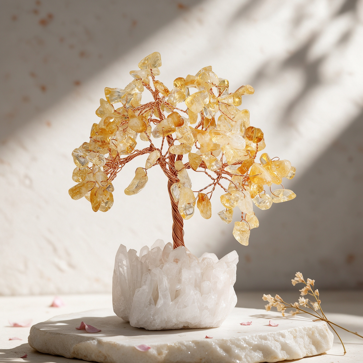 Handcrafted citrine crystal tree with golden gemstone chip leaves and a raw clear quartz cluster base, displayed on white stone in warm window light
